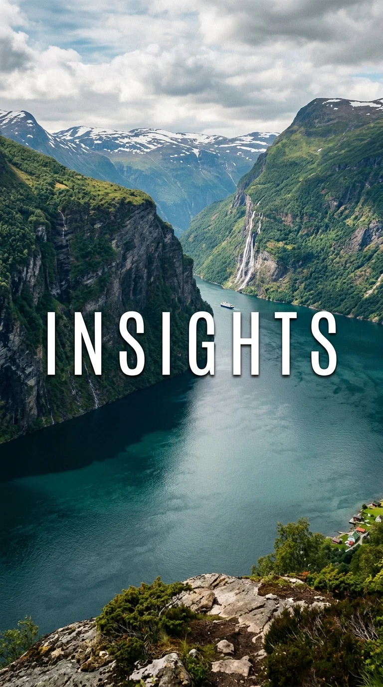 Waterfall descending between green cliffs into a deep blue fjord.